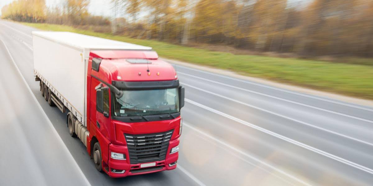 Red commercial truck driving on a highway, representing a commercial truck accident scenario involving large business vehicles