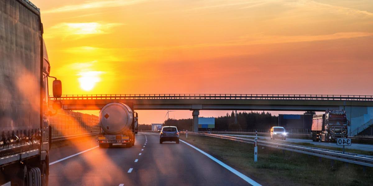 Trucks and cars traveling on a highway at sunset, representing interstate trucking routes that may affect legal claims